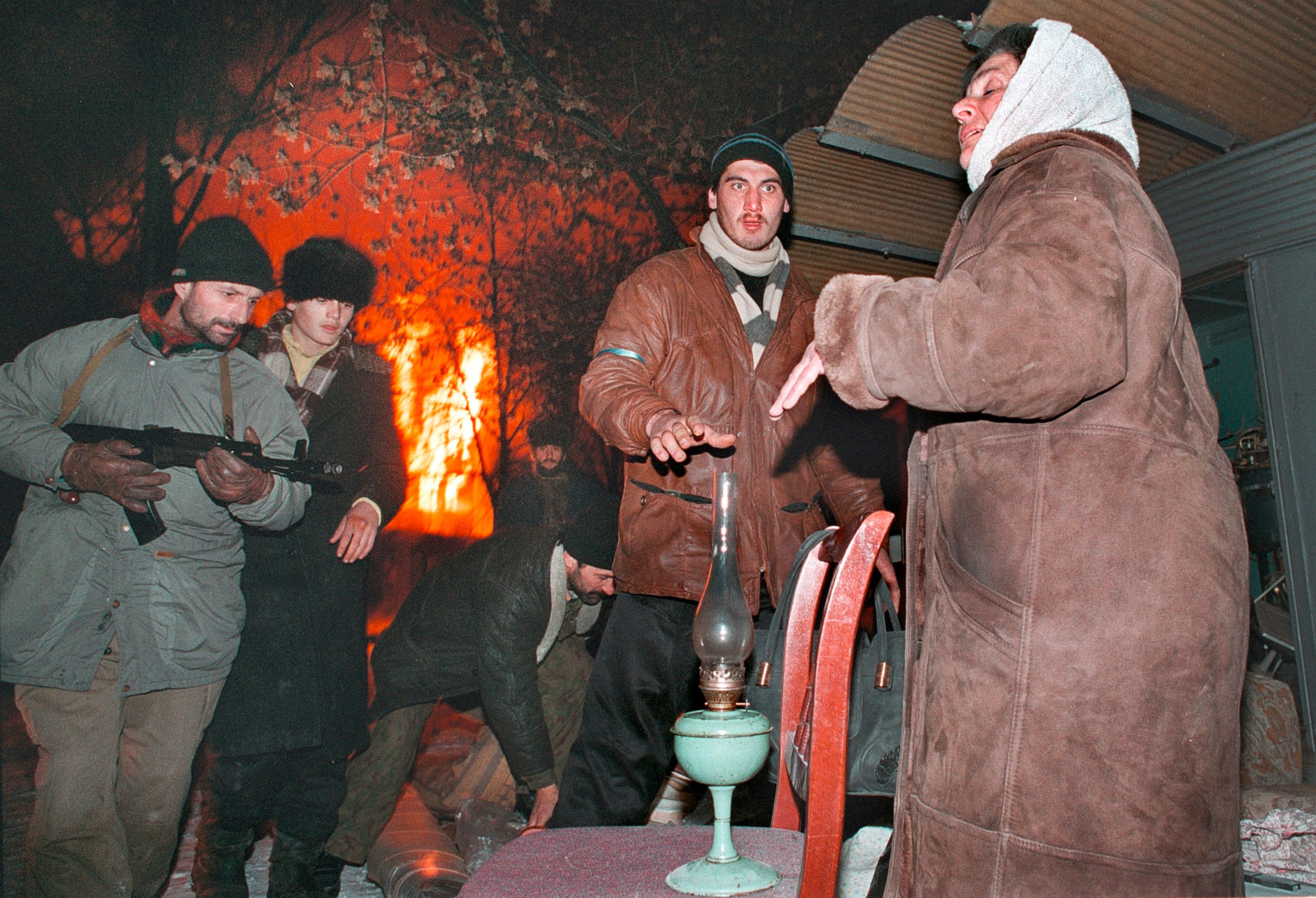 Боевики помогают женщине, которая покидает горящий Грозный. Декабрь 1994. Фото: Александр Неменов&nbsp;