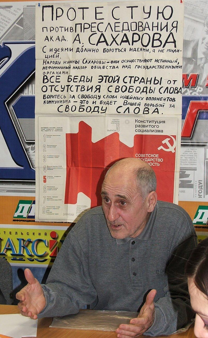 Вазиф Мейланов. За его спиной — тот самый плакат