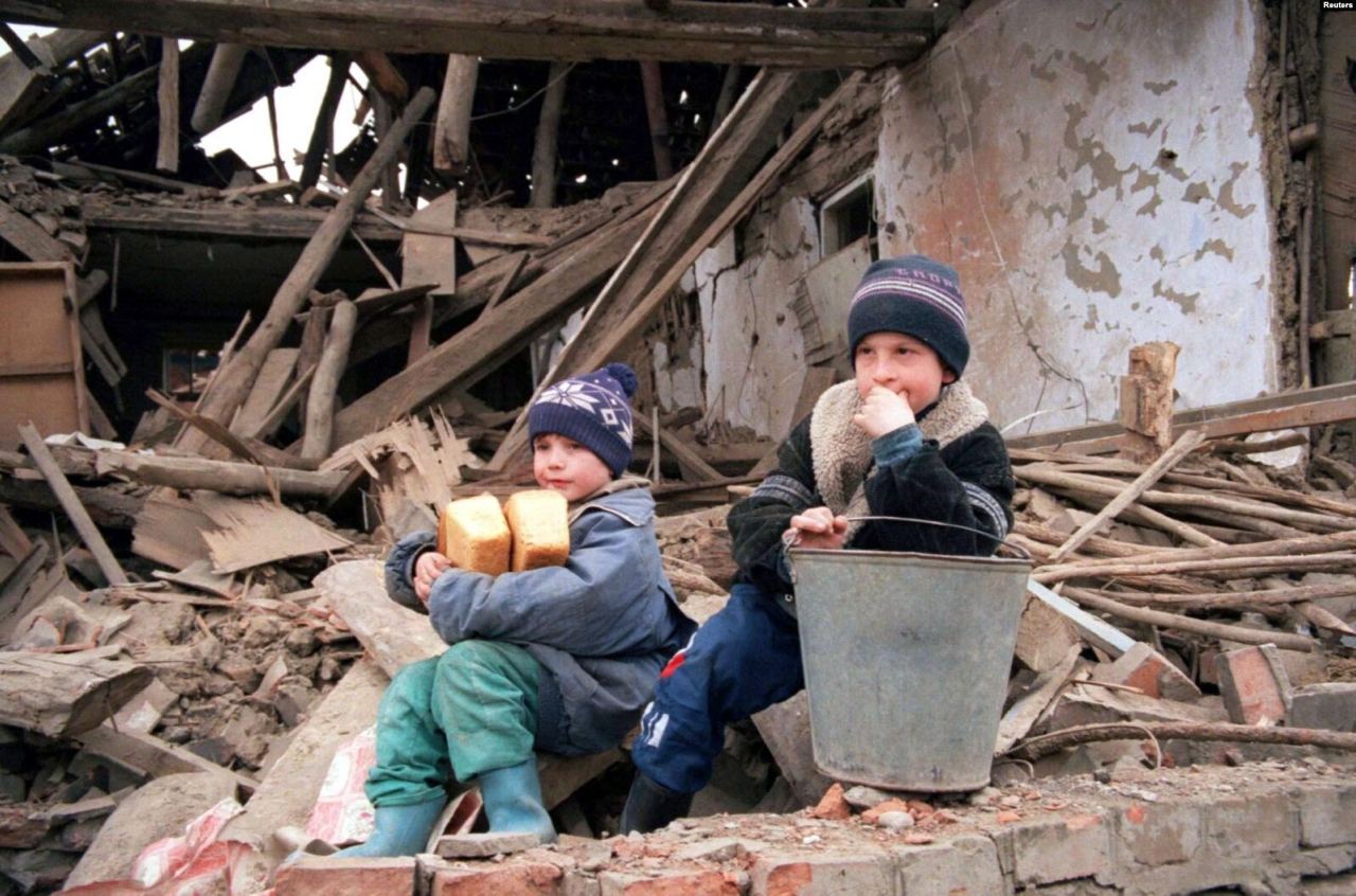 Chechen boys sit next to a destroyed house after buying some bread in Samashki April 9 (фото:&nbsp;Stringer/REUTERS)